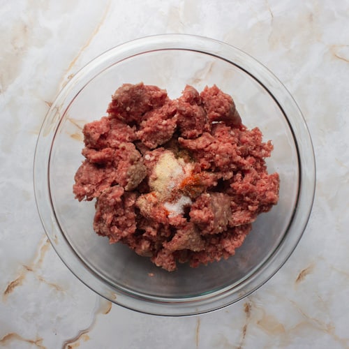 Ground beef and seasoning in a bowl