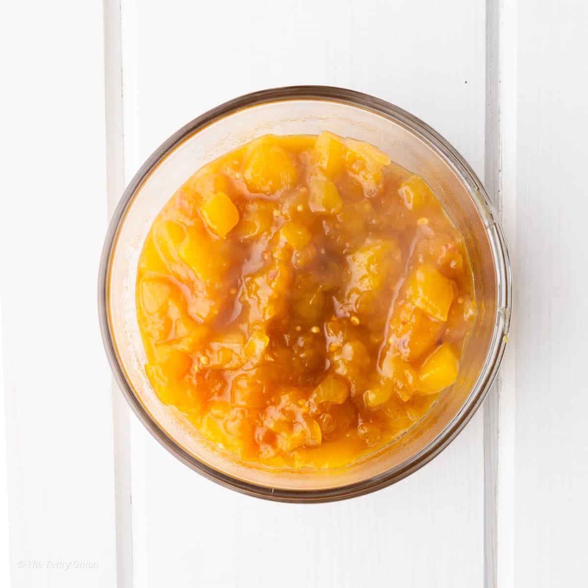 Homemade mango chutney in a clear glass dish.