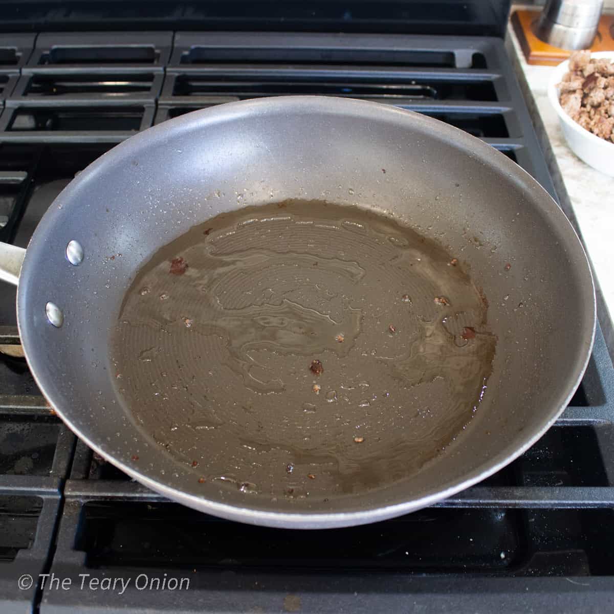 A frying pan with a coating of beef fat in the bottom.