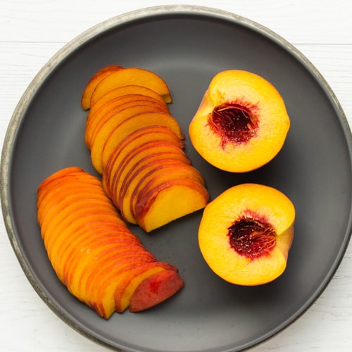 Halved and sliced peaches on a plate.