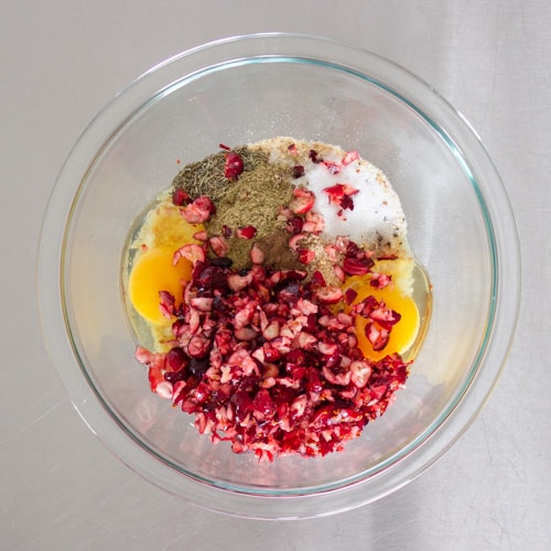 cranberries, breadcrumbs, eggs and herbs in a clear glass bowl