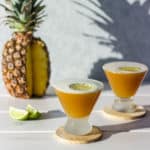 two Spicy Pineapple Rum Cocktail sitting on wooden coasters