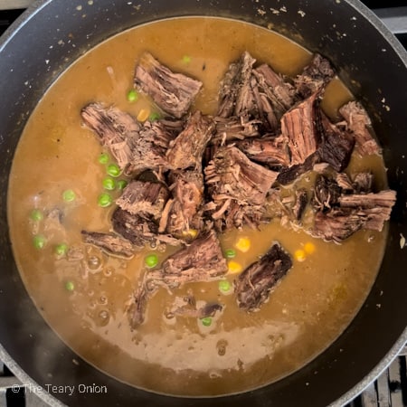adding the beef, corn and peas to the stew