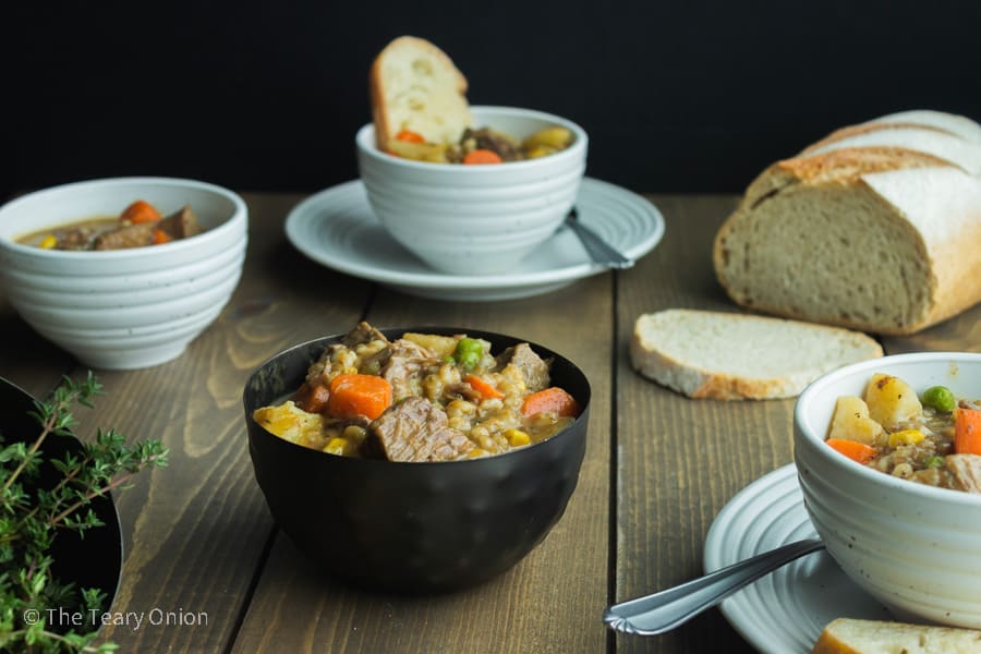 random bowls of slow cooked beef stew with a loaf of bread