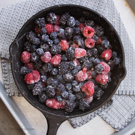mixed berries tossed with sugar and cornstarch in a cast iron pan