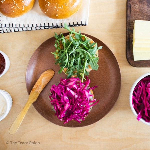 Pickled cabbage and arugula added to a burger
