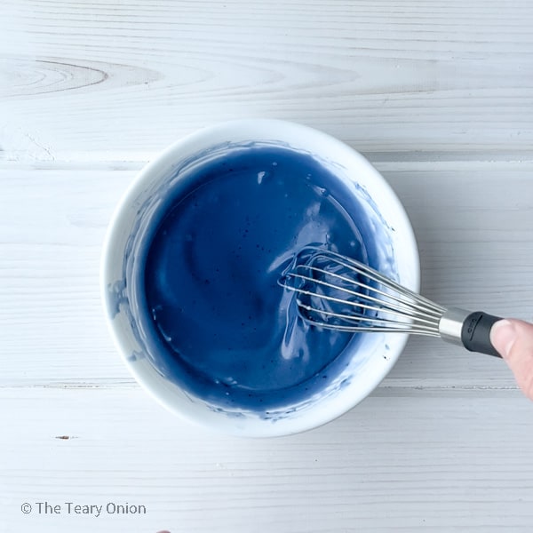 stirring butterfly pea flower powder into white chocolate mixture