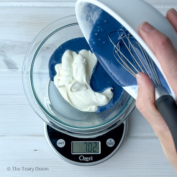pouring blue white chocolate mixture into whipped cream