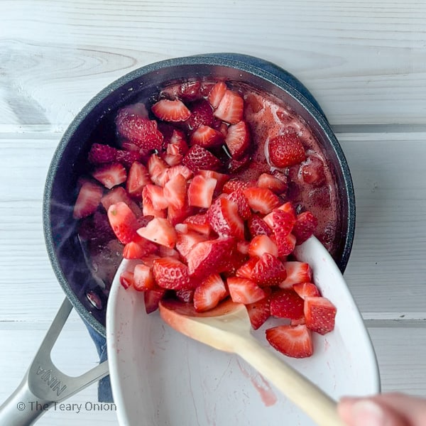 mixing fresh strawberries into the cooked strawberries