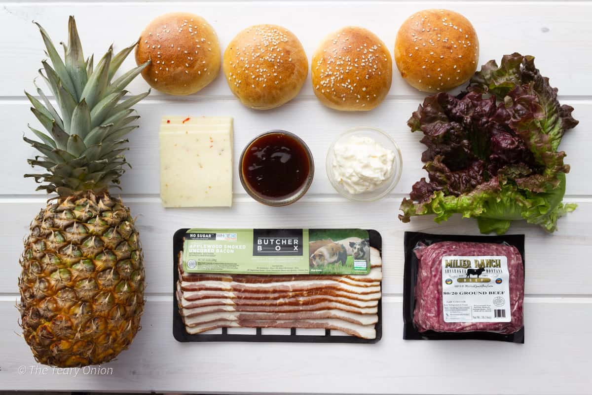 Ingredients for teriyaki burgers with pineapple on a white board.