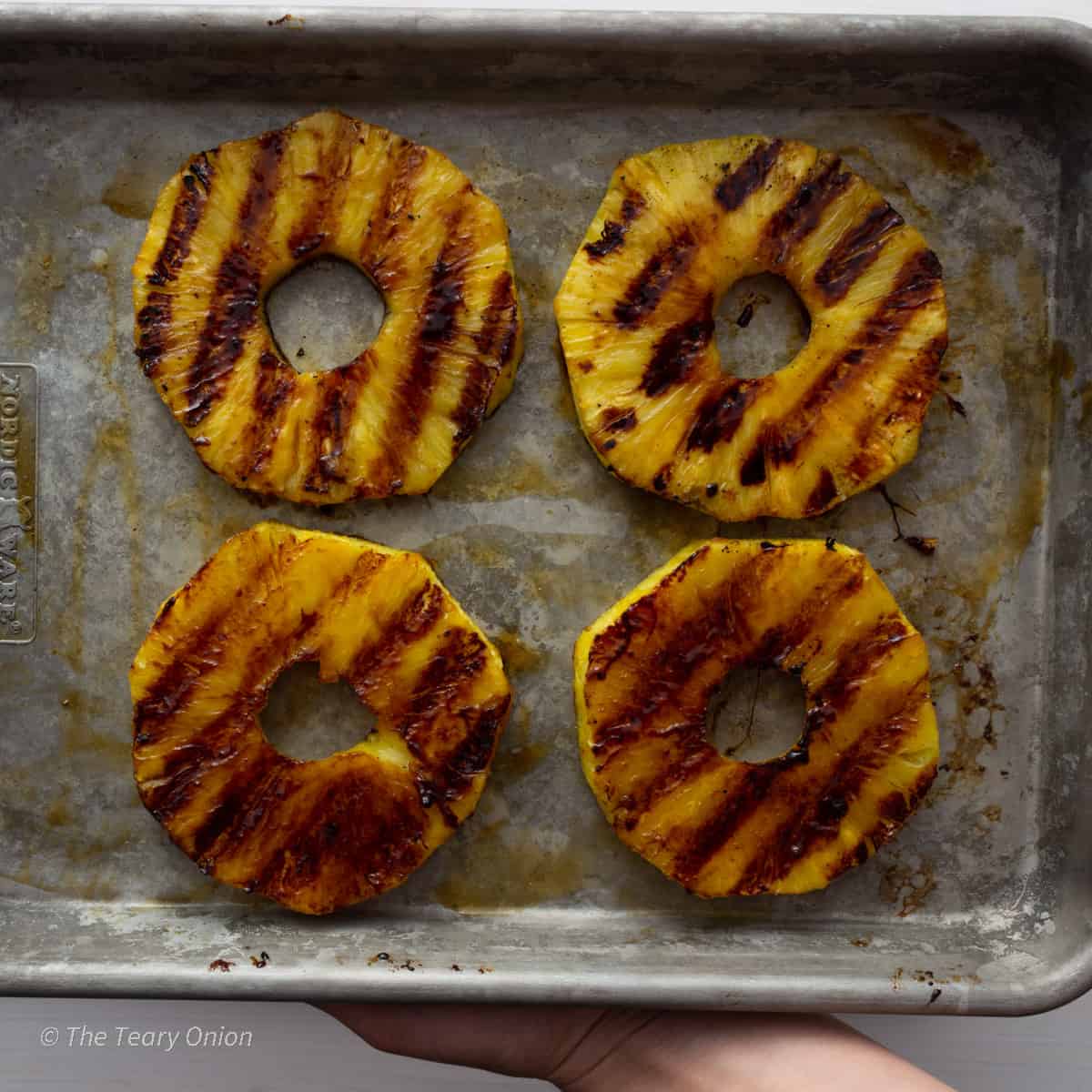 Grilled pineapple rings on a tray.